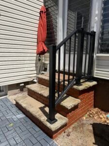 Black metal balcony railing custom fitted to an elevated outdoor space in New JerseyCaption: A custom metal balcony railing gives the elevated area a strong, clean, and finished appearance.Description: Black metal balcony railing fabricated to fit an elevated residential outdoor area in New Jersey.